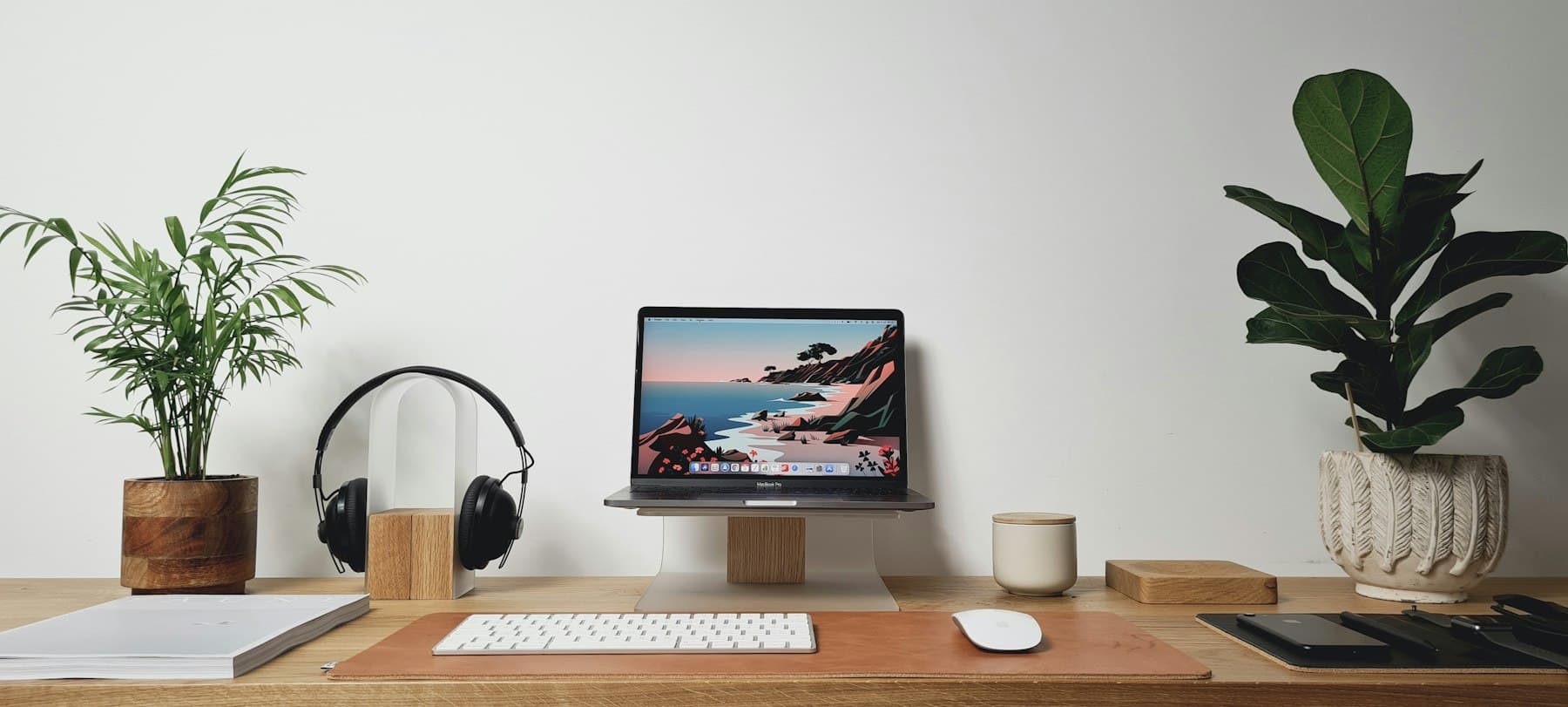 A bright room with an iMac on a wooden desk between two plants