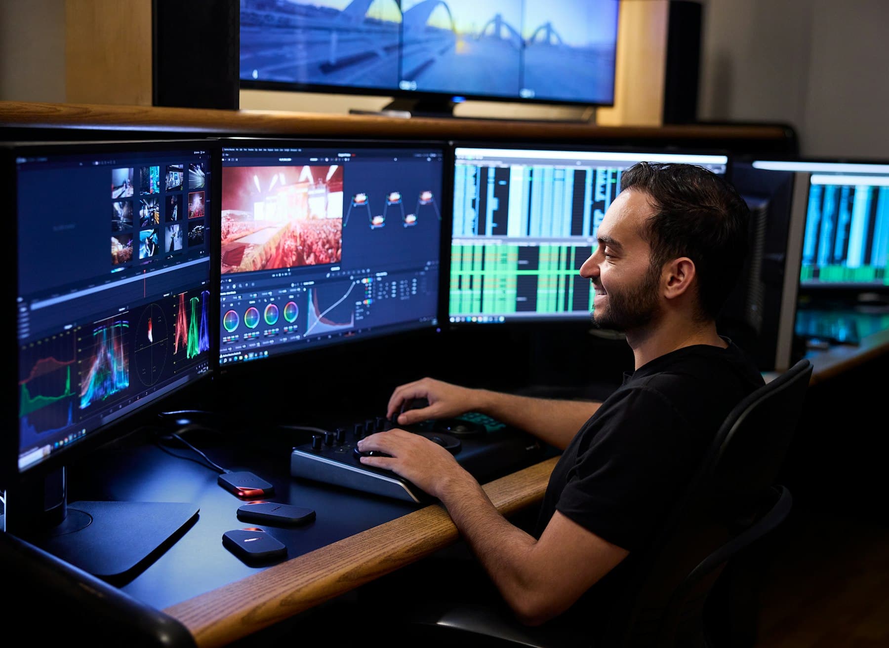A man editing video across several monitors