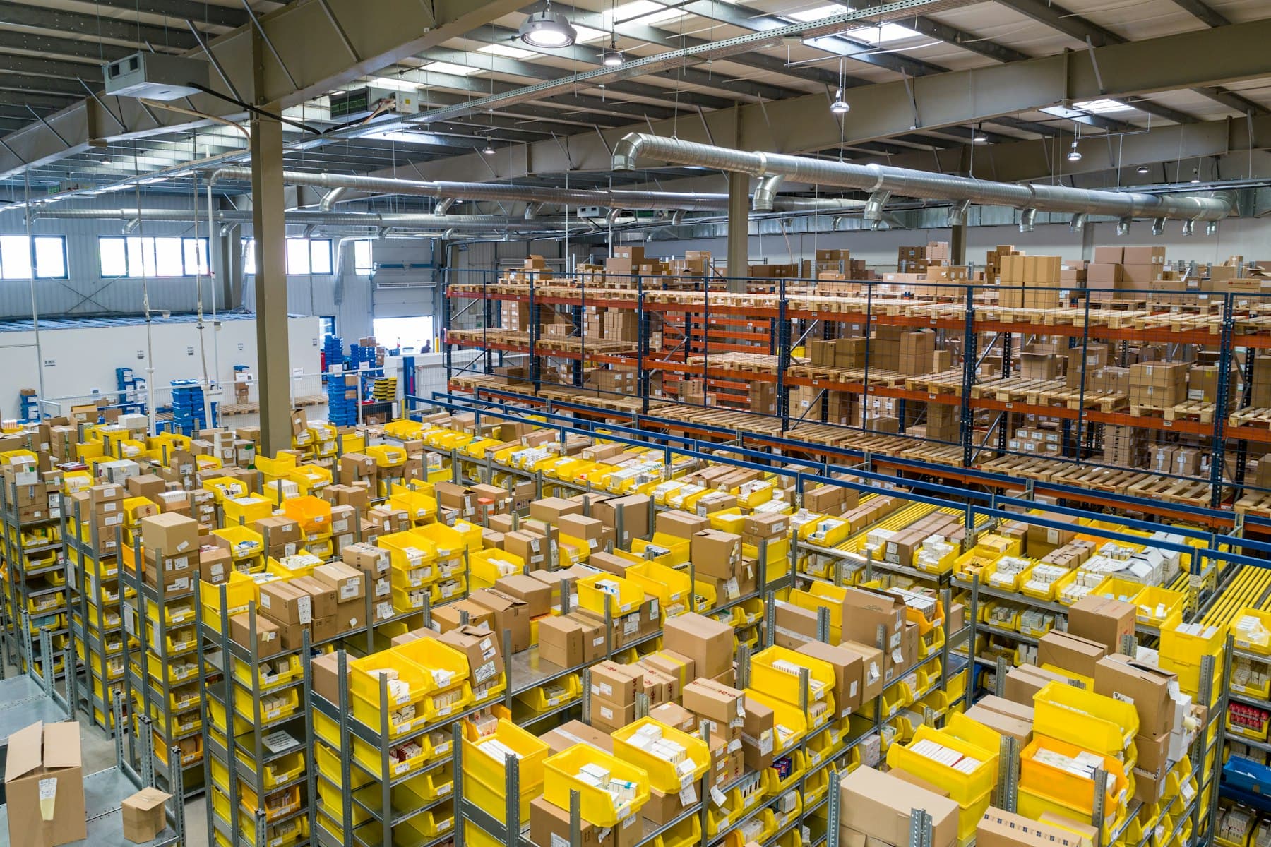 Rows of yellow crates and shelving in a large distribution warehouse