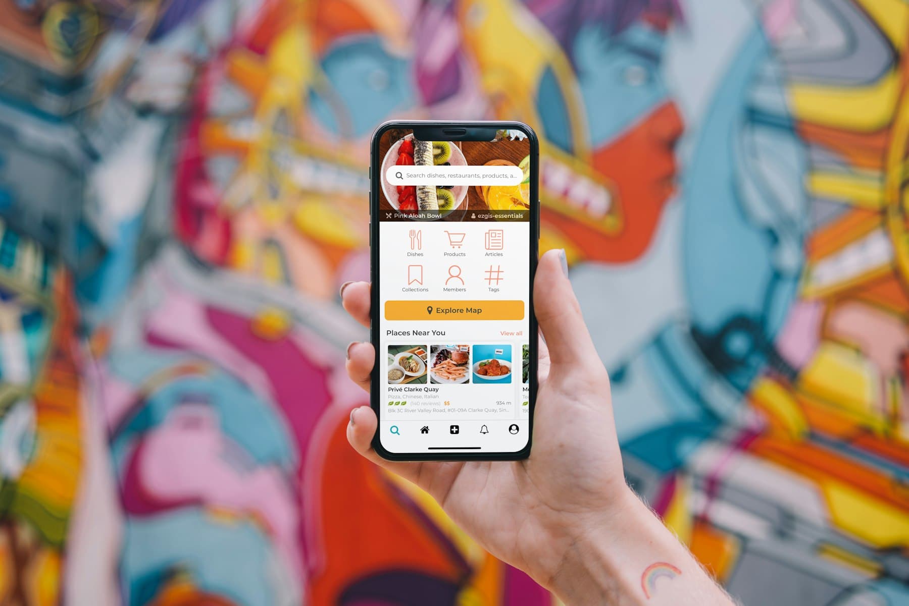 A hand holding a phone with a shopping app against a colorful mural